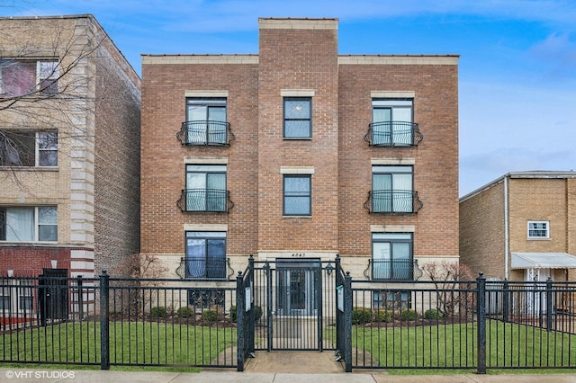 view of property with a fenced front yard, a front yard, and brick siding