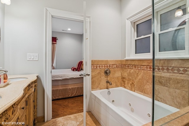 ensuite bathroom featuring tile patterned floors, vanity, a tub with jets, and ensuite bathroom