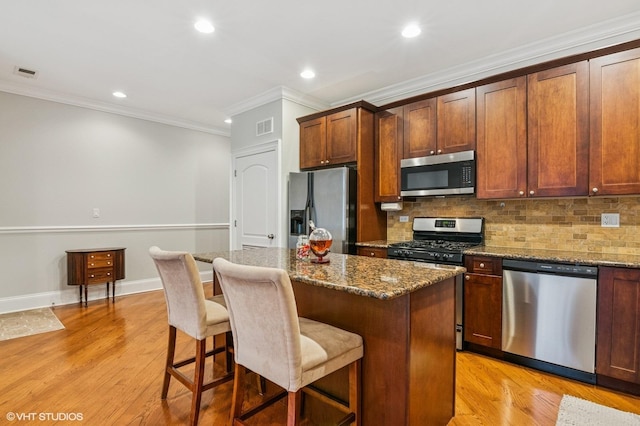 kitchen featuring appliances with stainless steel finishes, visible vents, light wood-style floors, and backsplash