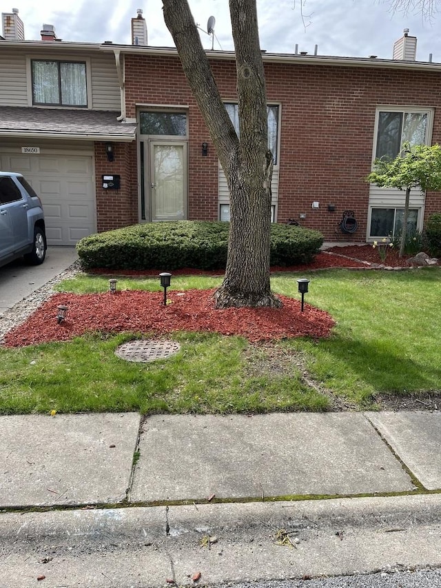 view of front of property featuring a garage, brick siding, a chimney, and a front lawn