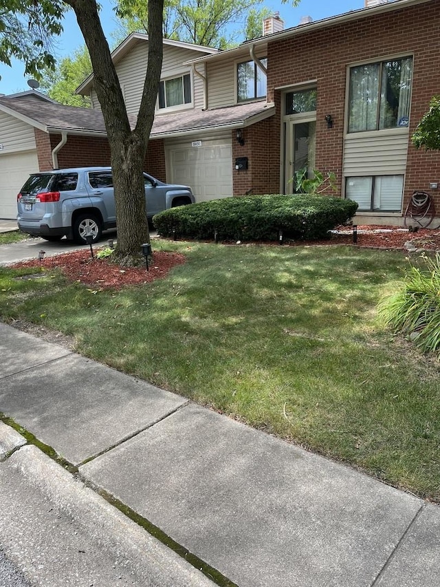 view of front of property featuring concrete driveway, brick siding, a chimney, and a front lawn