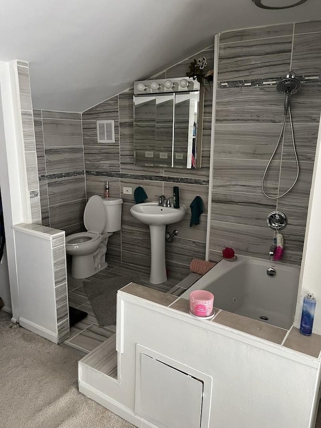 full bathroom featuring visible vents, toilet, a combined bath / shower with jetted tub, vaulted ceiling, and tile walls