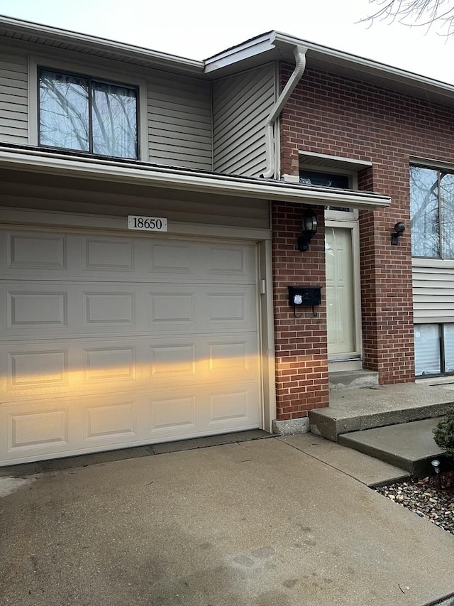 exterior space featuring a garage, driveway, and brick siding