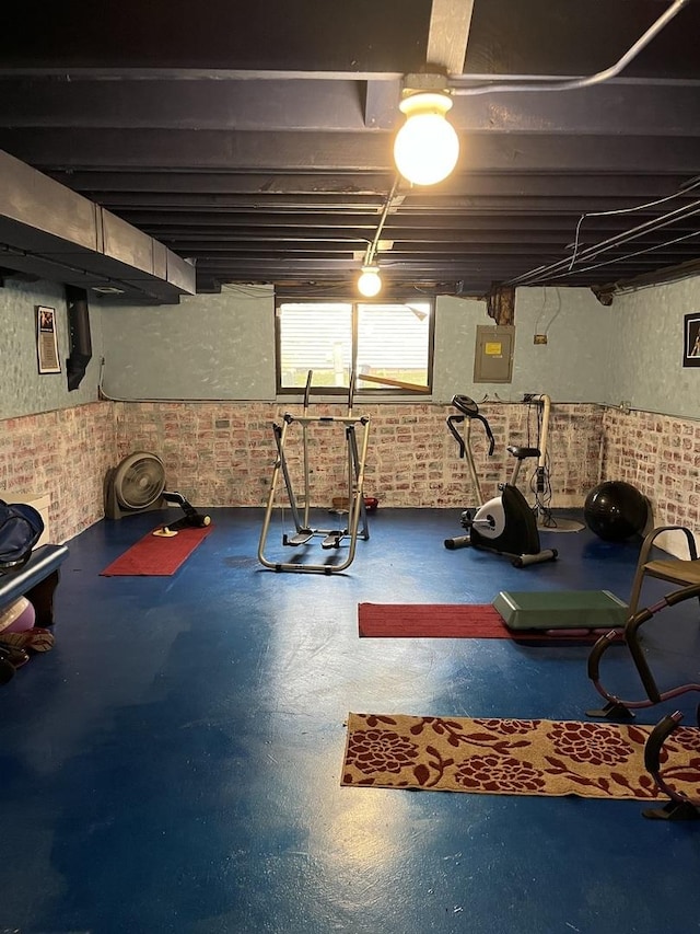 exercise area featuring brick wall and electric panel