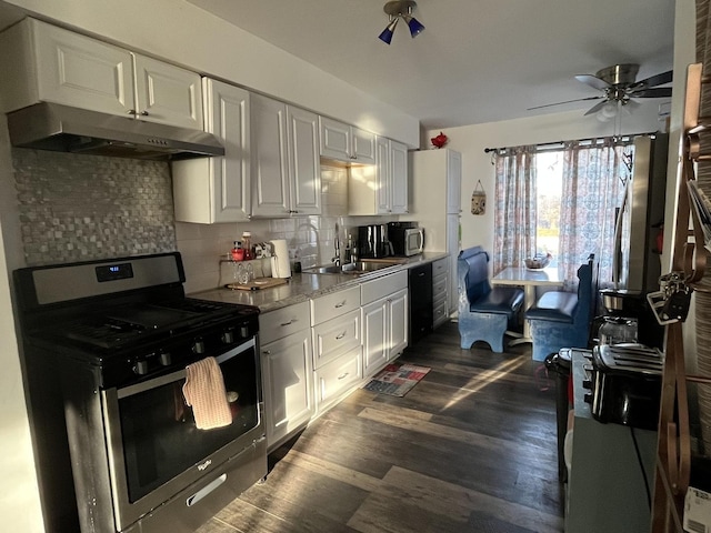 kitchen featuring dark wood-style flooring, tasteful backsplash, a sink, gas range, and under cabinet range hood