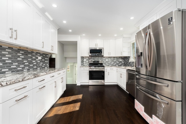 kitchen featuring stainless steel appliances, dark wood finished floors, light stone countertops, and white cabinets