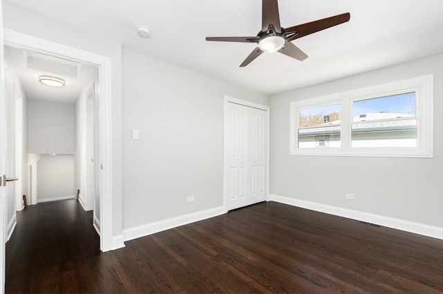 unfurnished bedroom with visible vents, baseboards, dark wood finished floors, ceiling fan, and a closet