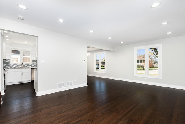 unfurnished living room featuring baseboards, dark wood-style flooring, a sink, and recessed lighting