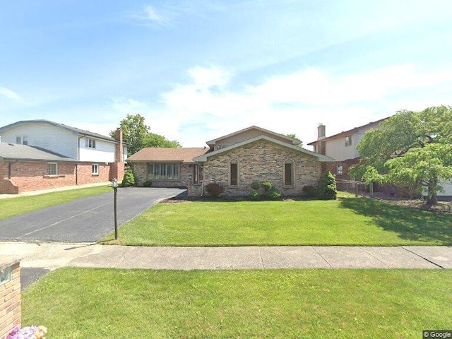 view of front of home with aphalt driveway, brick siding, and a front lawn