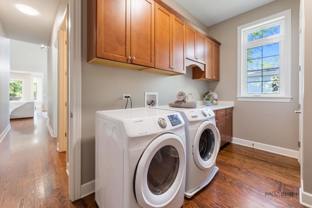 washroom with dark wood-type flooring, baseboards, cabinet space, and washing machine and clothes dryer