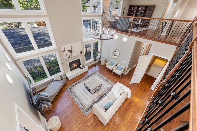 living area with a wealth of natural light, a glass covered fireplace, and a towering ceiling