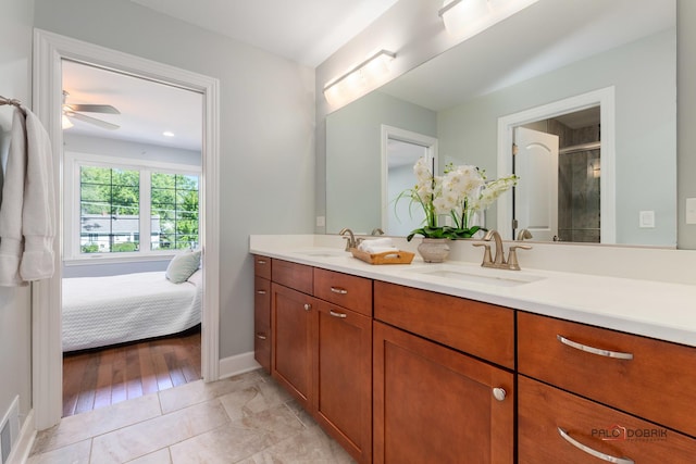 bathroom with double vanity, a stall shower, a sink, and a ceiling fan