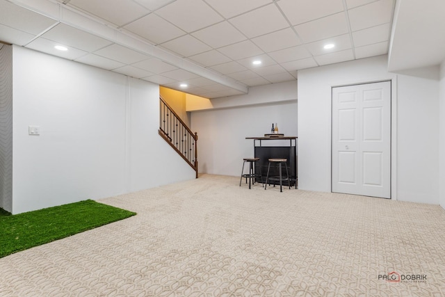 finished basement featuring recessed lighting, a paneled ceiling, stairway, carpet flooring, and a bar