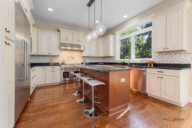 kitchen with premium appliances, dark wood finished floors, a kitchen island, and exhaust hood