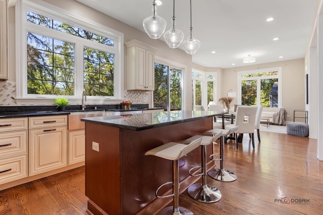 kitchen featuring dark stone countertops, a kitchen bar, backsplash, and dark wood-style flooring