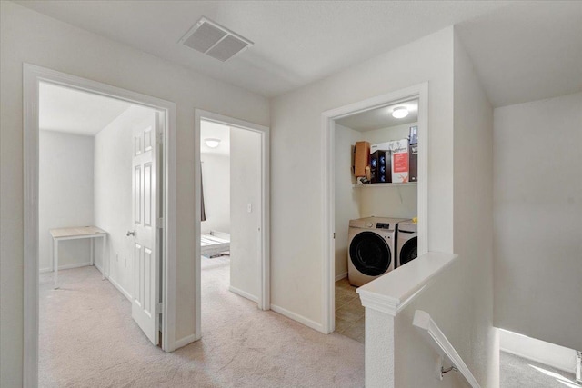 hall with visible vents, baseboards, separate washer and dryer, carpet flooring, and an upstairs landing