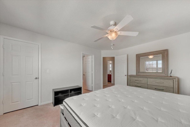 bedroom featuring baseboards, light colored carpet, ceiling fan, and a textured ceiling