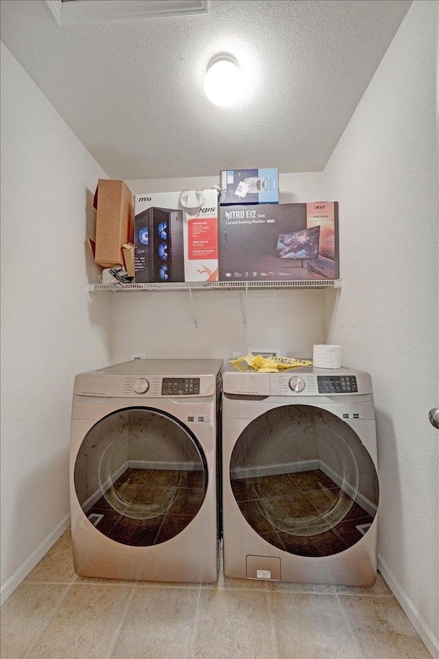 washroom featuring laundry area, washing machine and dryer, a textured ceiling, and baseboards