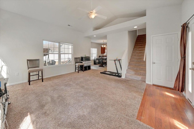 workout room featuring visible vents, baseboards, carpet flooring, ceiling fan with notable chandelier, and high vaulted ceiling