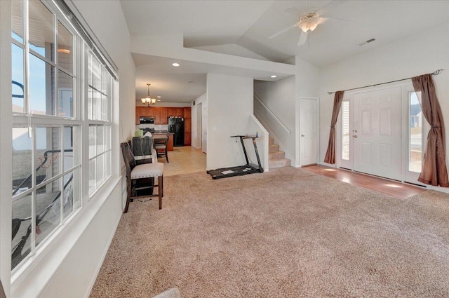 foyer entrance with stairway, light carpet, visible vents, and vaulted ceiling