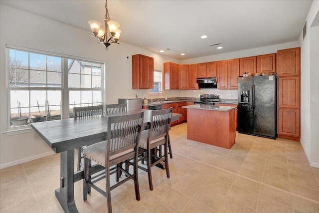 kitchen with range with electric cooktop, black fridge, a sink, a kitchen island, and hanging light fixtures