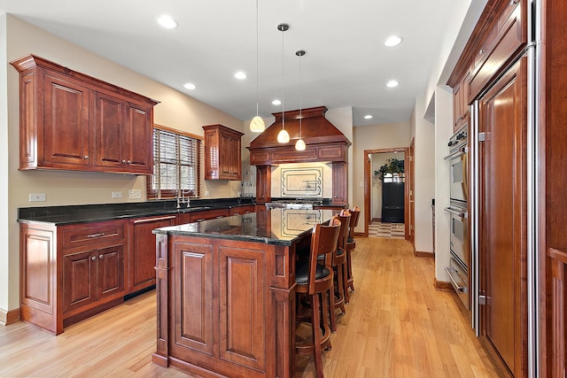 kitchen with recessed lighting, a kitchen island, a kitchen breakfast bar, light wood-type flooring, and decorative light fixtures