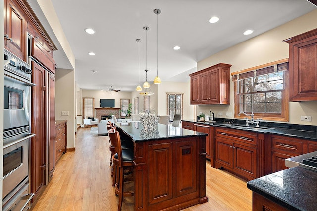 kitchen with open floor plan, stainless steel double oven, a fireplace, a sink, and a warming drawer