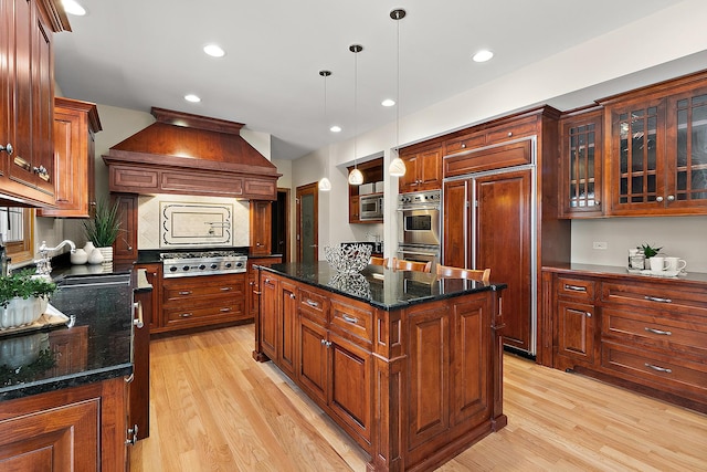 kitchen with built in appliances, a center island, light wood-style flooring, and custom range hood