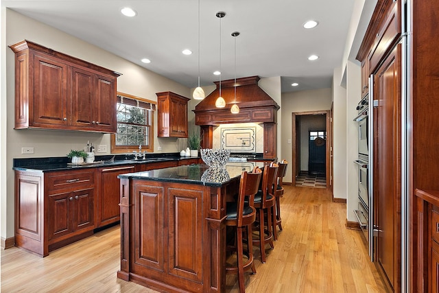 kitchen with premium range hood, a kitchen island, light wood-style flooring, and recessed lighting