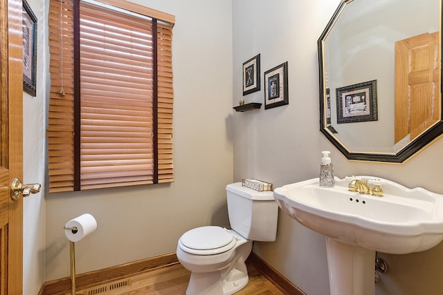 bathroom featuring visible vents, toilet, a sink, wood finished floors, and baseboards