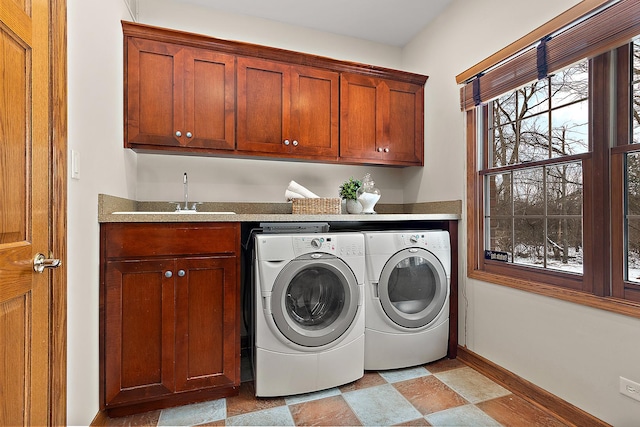 clothes washing area featuring washer and clothes dryer, a sink, cabinet space, and baseboards