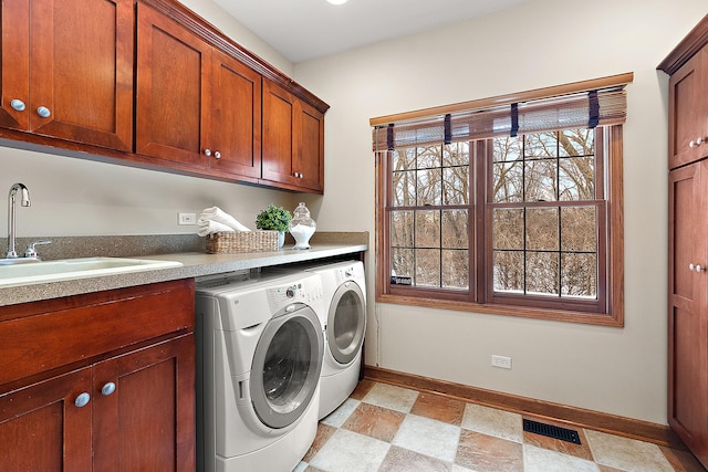 laundry room with cabinet space, baseboards, visible vents, washer and clothes dryer, and a sink