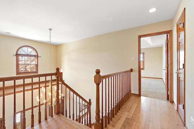 corridor featuring baseboards, wood finished floors, an upstairs landing, a notable chandelier, and recessed lighting