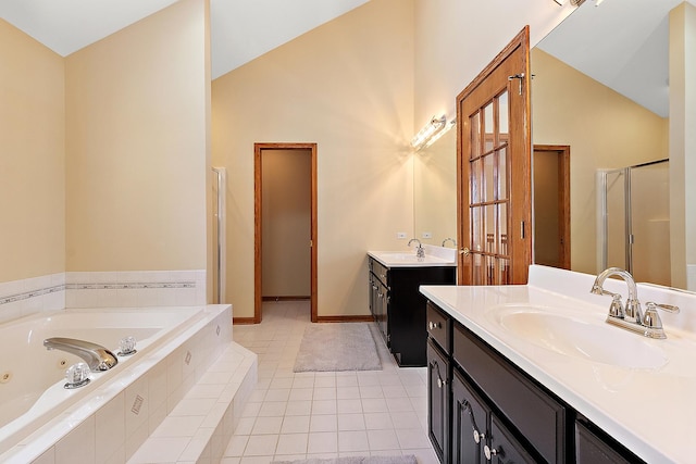 bathroom with lofted ceiling, a tub with jets, two vanities, and a sink