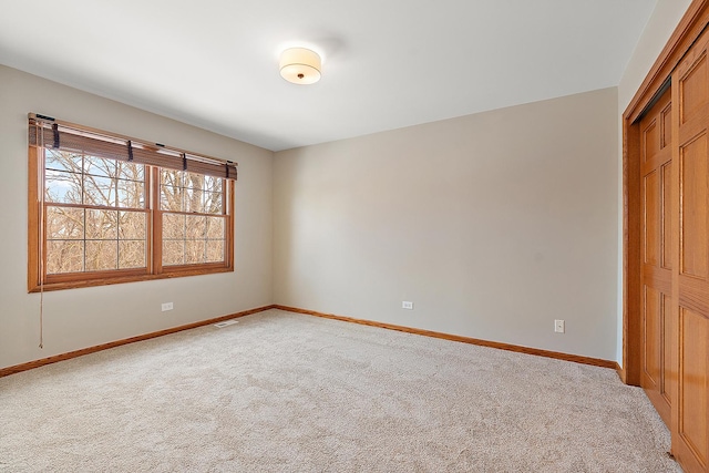 unfurnished room with light colored carpet and baseboards