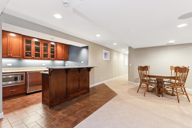 kitchen with stainless steel microwave, a kitchen bar, and recessed lighting