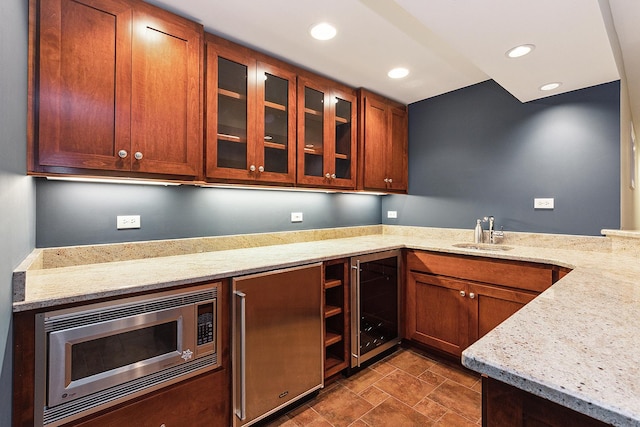 kitchen featuring recessed lighting, stainless steel microwave, glass insert cabinets, a sink, and beverage cooler