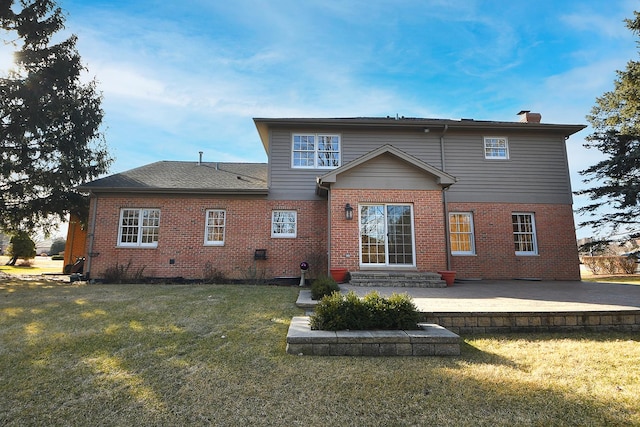 back of property featuring a yard, brick siding, a chimney, and a patio area