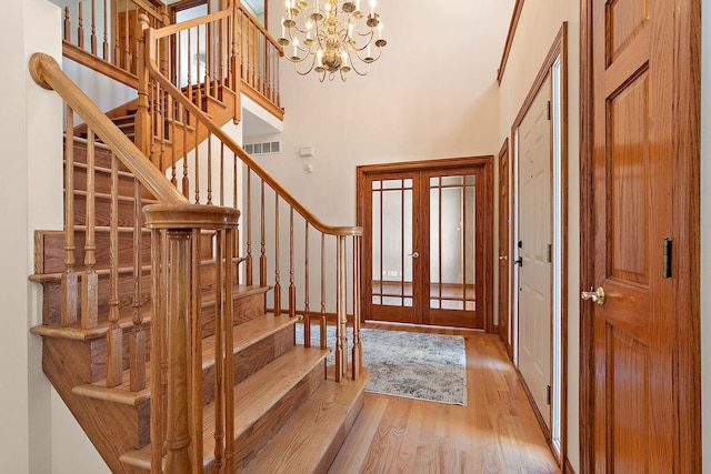 entrance foyer featuring visible vents, a towering ceiling, french doors, stairway, and light wood-type flooring