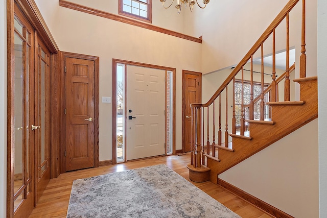 foyer with stairs, a high ceiling, baseboards, and wood finished floors