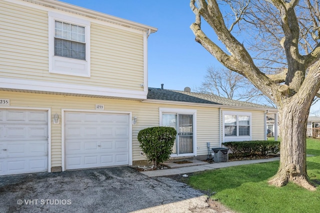 view of front of property with a garage, a front lawn, central AC, and driveway