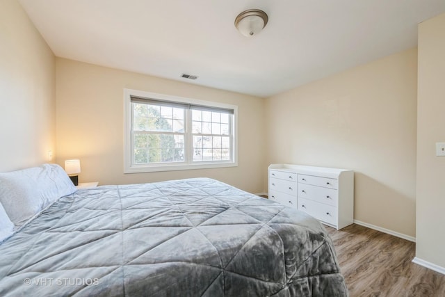 bedroom with visible vents, baseboards, and wood finished floors