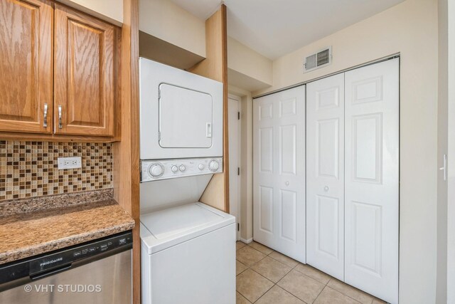 washroom with laundry area, light tile patterned flooring, visible vents, and stacked washer and clothes dryer