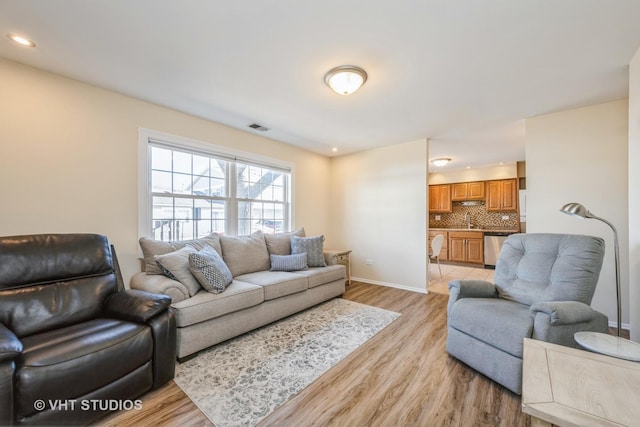 living room with recessed lighting, baseboards, visible vents, and light wood finished floors