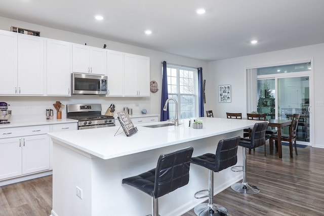 kitchen with stainless steel appliances, a breakfast bar, dark wood-type flooring, and a sink