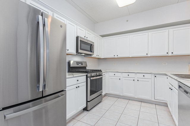 kitchen with light tile patterned floors, stainless steel appliances, light countertops, and white cabinetry