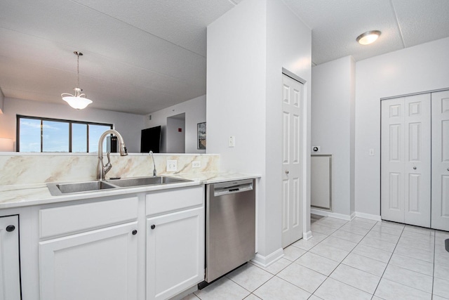 kitchen with pendant lighting, light tile patterned floors, stainless steel dishwasher, white cabinetry, and a sink