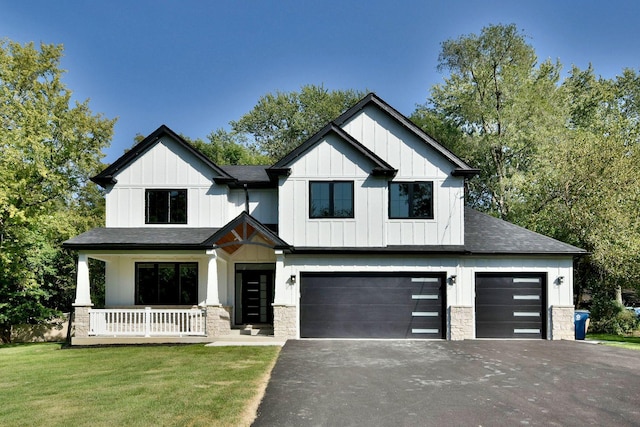 view of front of home featuring aphalt driveway, covered porch, stone siding, board and batten siding, and a front yard