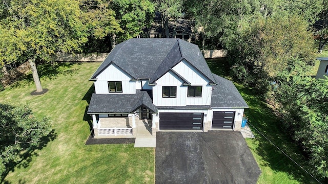 exterior space with driveway, an attached garage, a front lawn, a porch, and board and batten siding