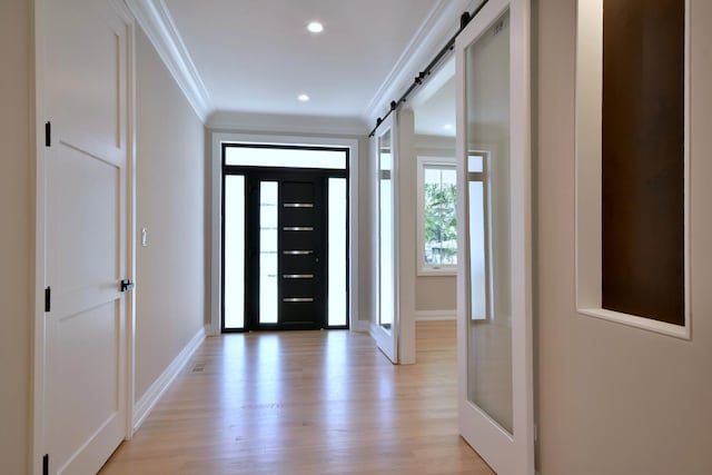 foyer with a barn door, light wood-style flooring, recessed lighting, baseboards, and crown molding